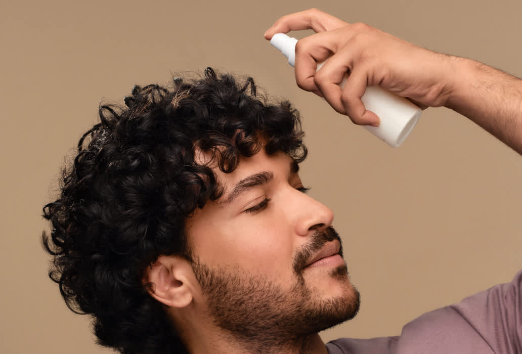 Мужчина наносит спрей для волос